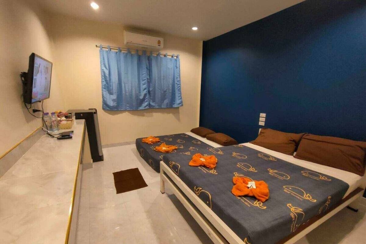 A hotel room with two beds, a TV, an air conditioner, and a blue curtain.