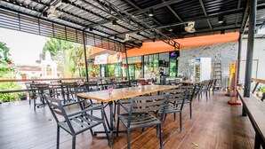Un restaurante con mesas y sillas de madera, piso de baldosas y vistas al exterior.