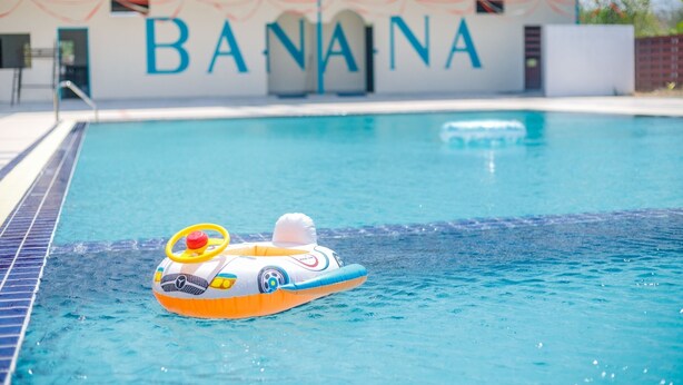 Una piscina con un objeto flotante y una pared con la palabra "BANANA" escrita en letras grandes.