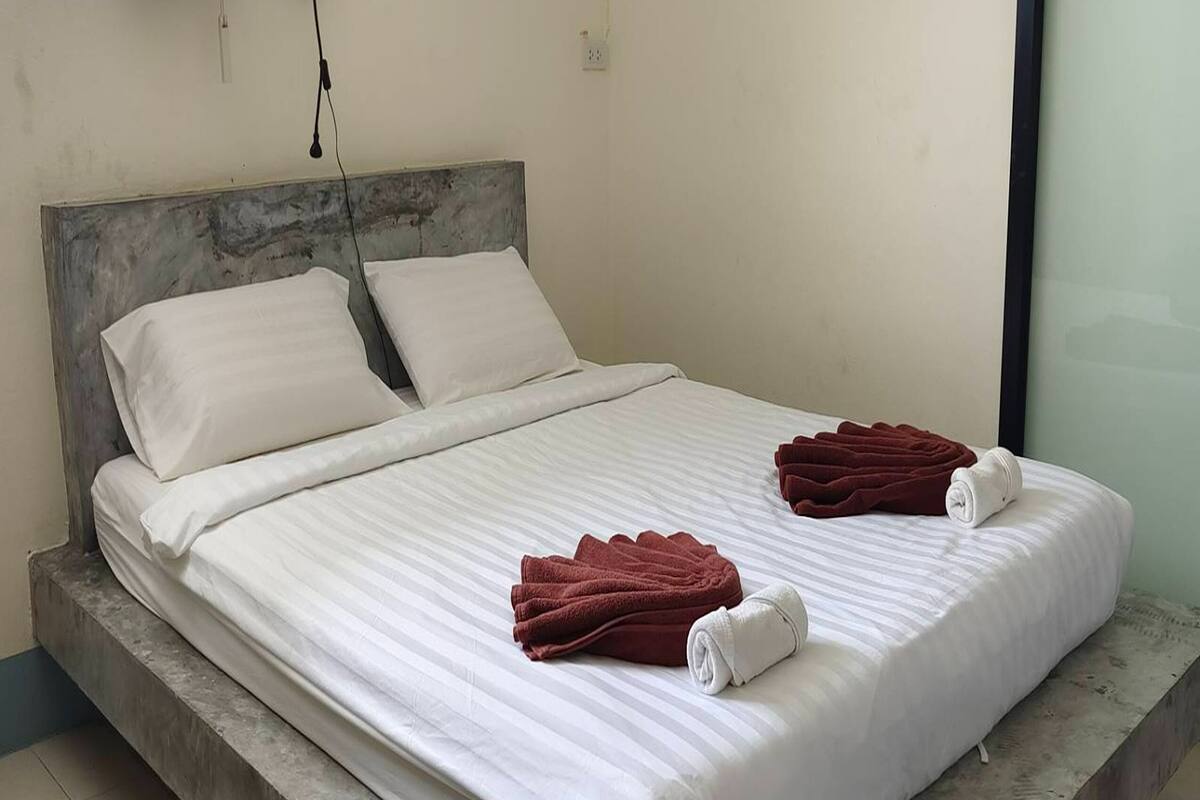 Ein Bett mit weißen Leinentüchern, zwei Kissen und zwei gefalteten Handtüchern an der Seite.
