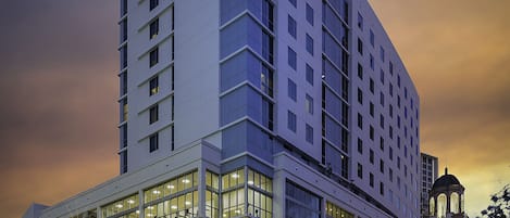Un hotel moderno con un llamativo letrero de "Hyatt Place", amplias ventanas y ubicación en una esquina con vista a la calle.