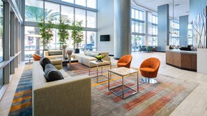 Un vestíbulo amplio con un sofá, sillones, una mesa de centro y una recepción.