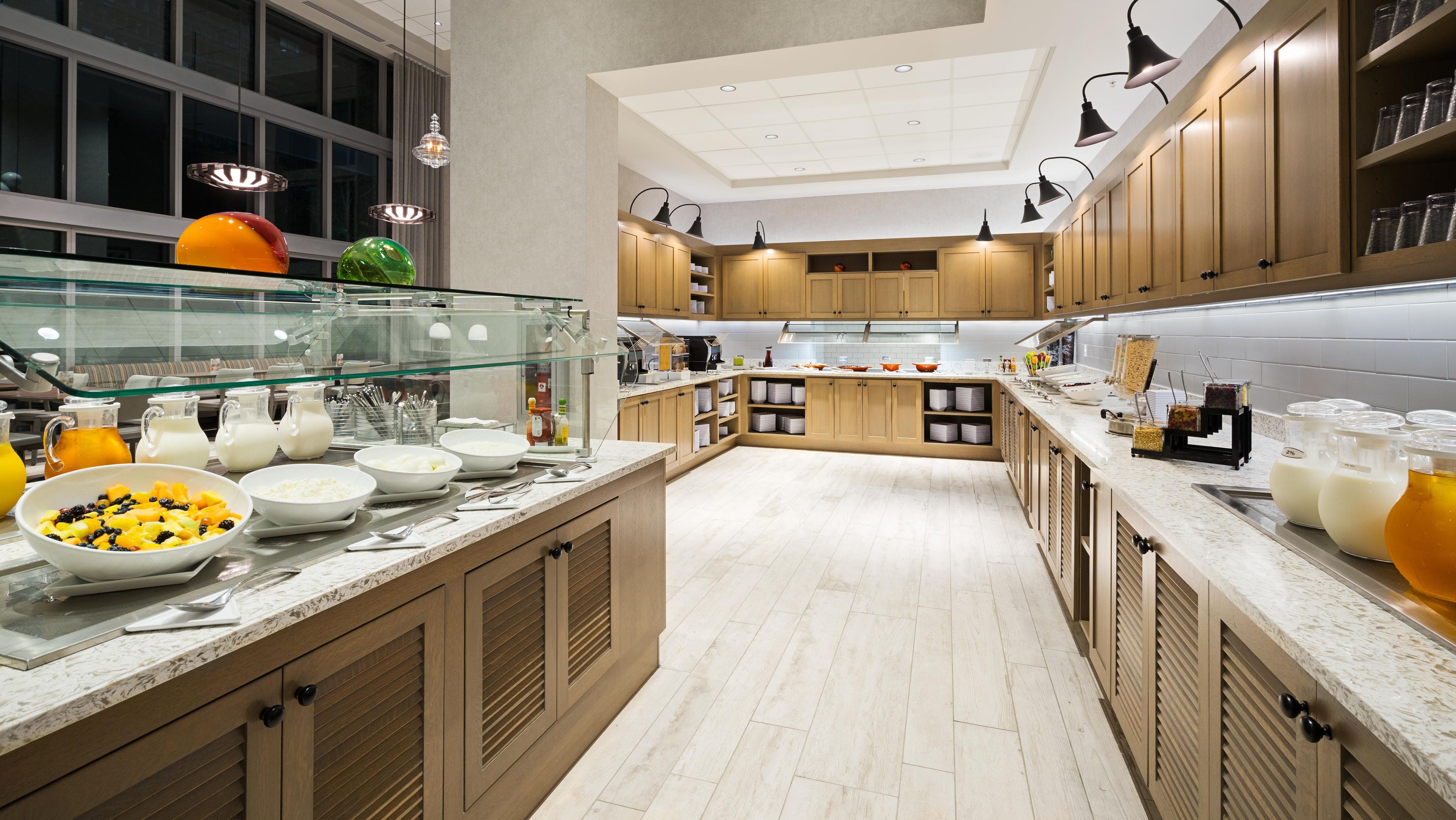 Une cuisine moderne avec des meubles en bois, une vitrine et divers produits alimentaires.