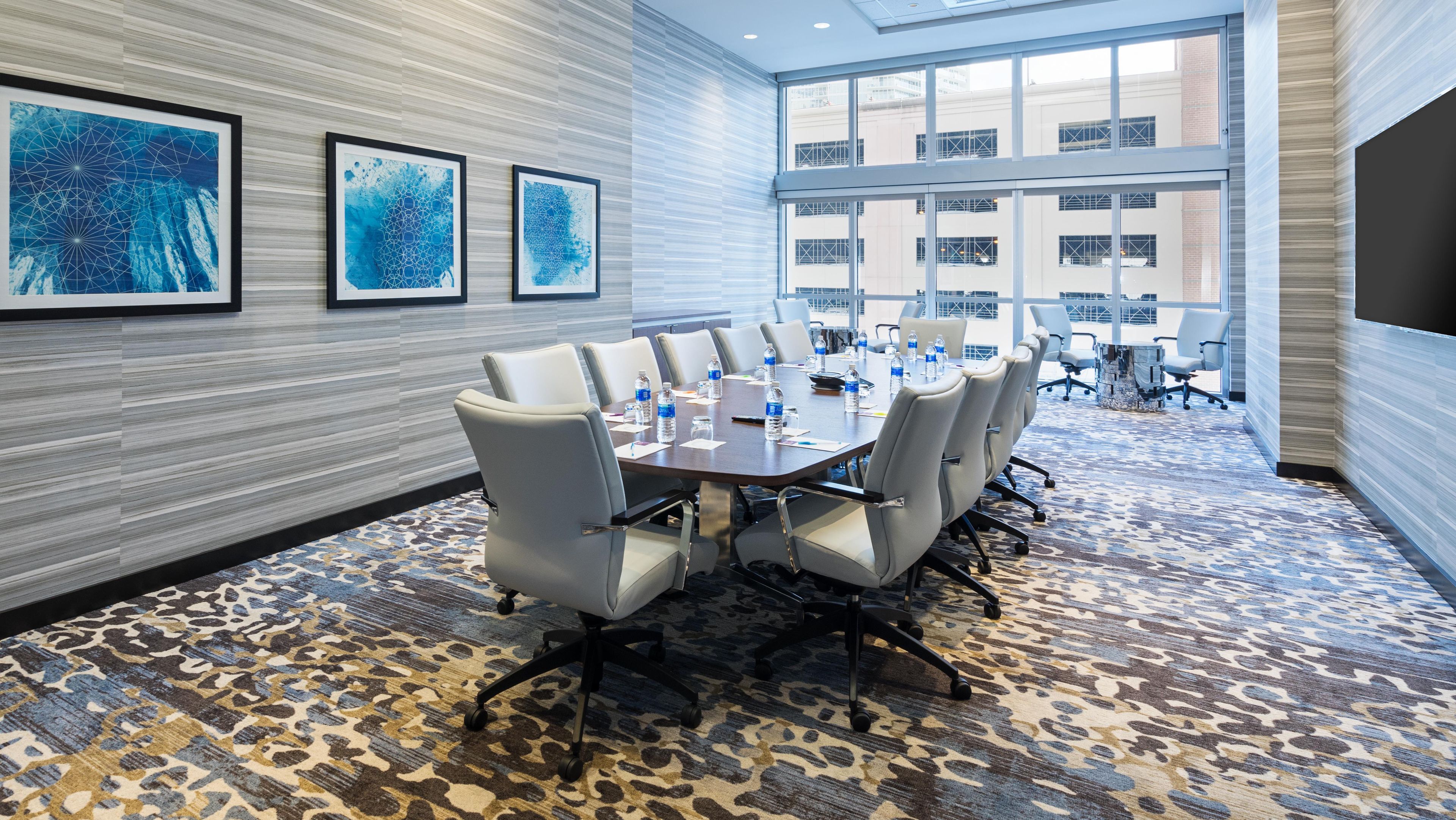 A conference room with a large table, chairs, and artwork on the walls.