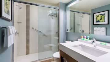 A modern bathroom with a glass-enclosed shower, a white sink with a mirror, and a toilet.