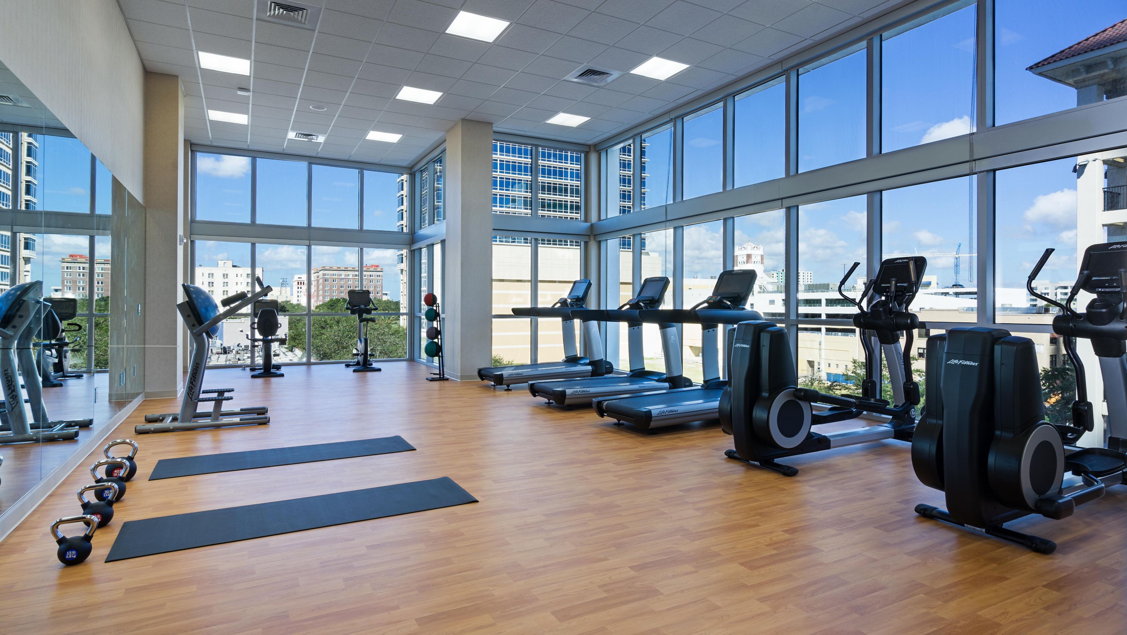 A gym with cardio machines, weights, and yoga mats.