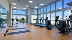 Un gimnasio con máquinas de cardio, pesas y colchonetas de yoga.