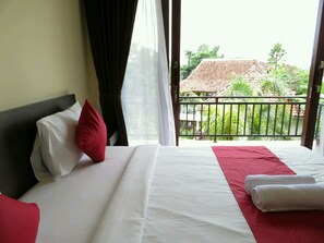 Una habitación de hotel con una cama, una almohada roja, una almohada blanca, un edredón rojo y una toalla blanca.