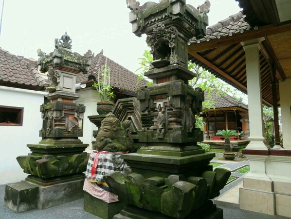 A courtyard with stone statues and a traditional tiled roof structure. - Odah Ayu Guest House (Ubud)