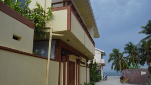A building with a balcony, a view of the ocean, and palm trees. - Sunshine View (Maafushi)