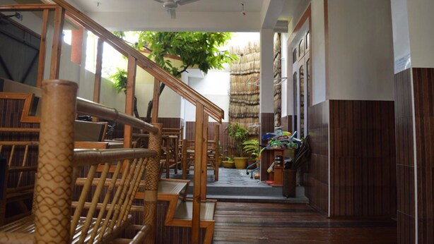 A wooden staircase leading to a room with a ceiling fan, potted plants, and a thatched roof structure. - Sunshine View (Maafushi)