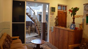 A reception area with a wooden desk, a clock, and a plant. - Sunshine View (Maafushi)