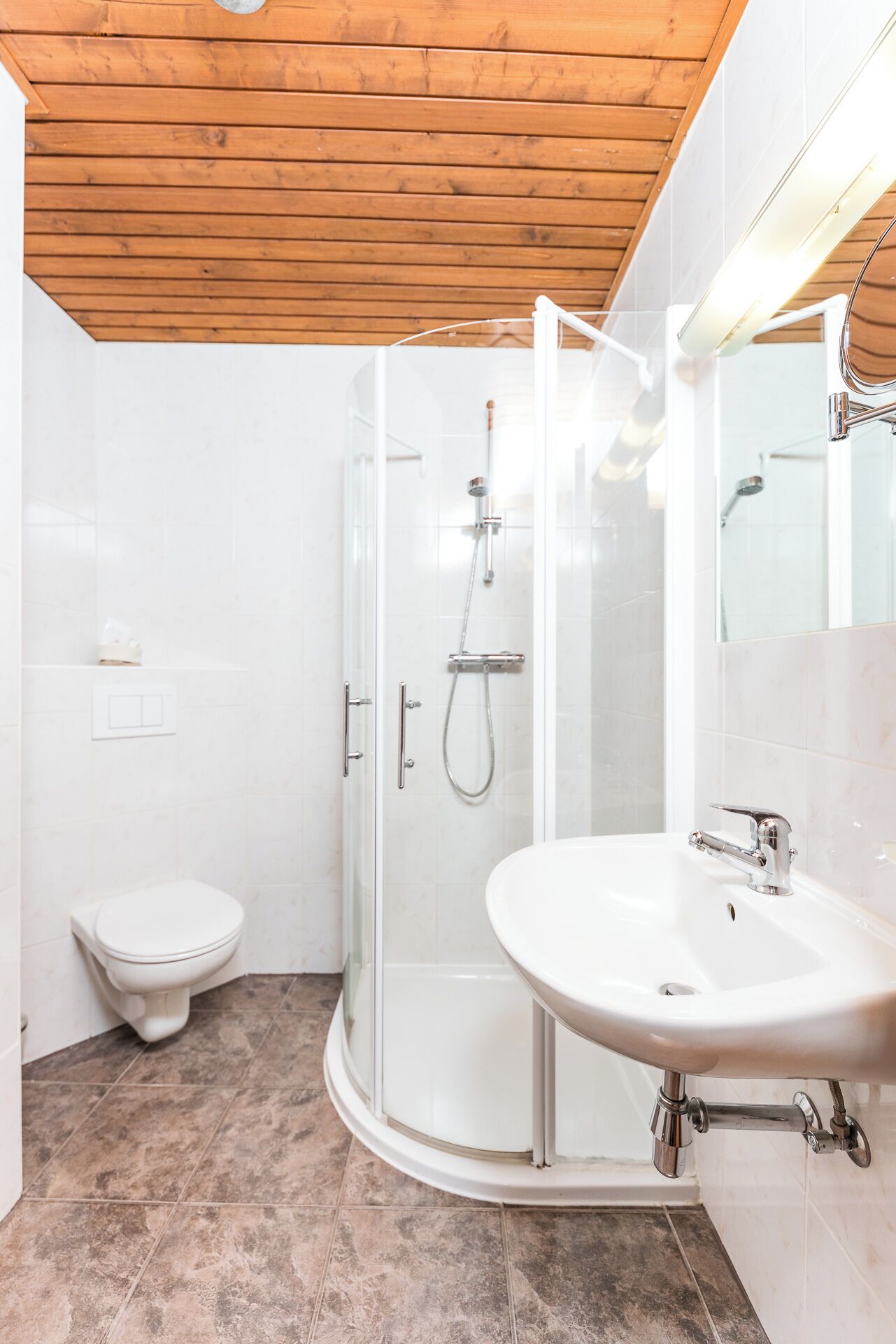 Une salle de bain moderne avec une douche à parois de verre, des toilettes blanches et un lavabo avec un miroir.