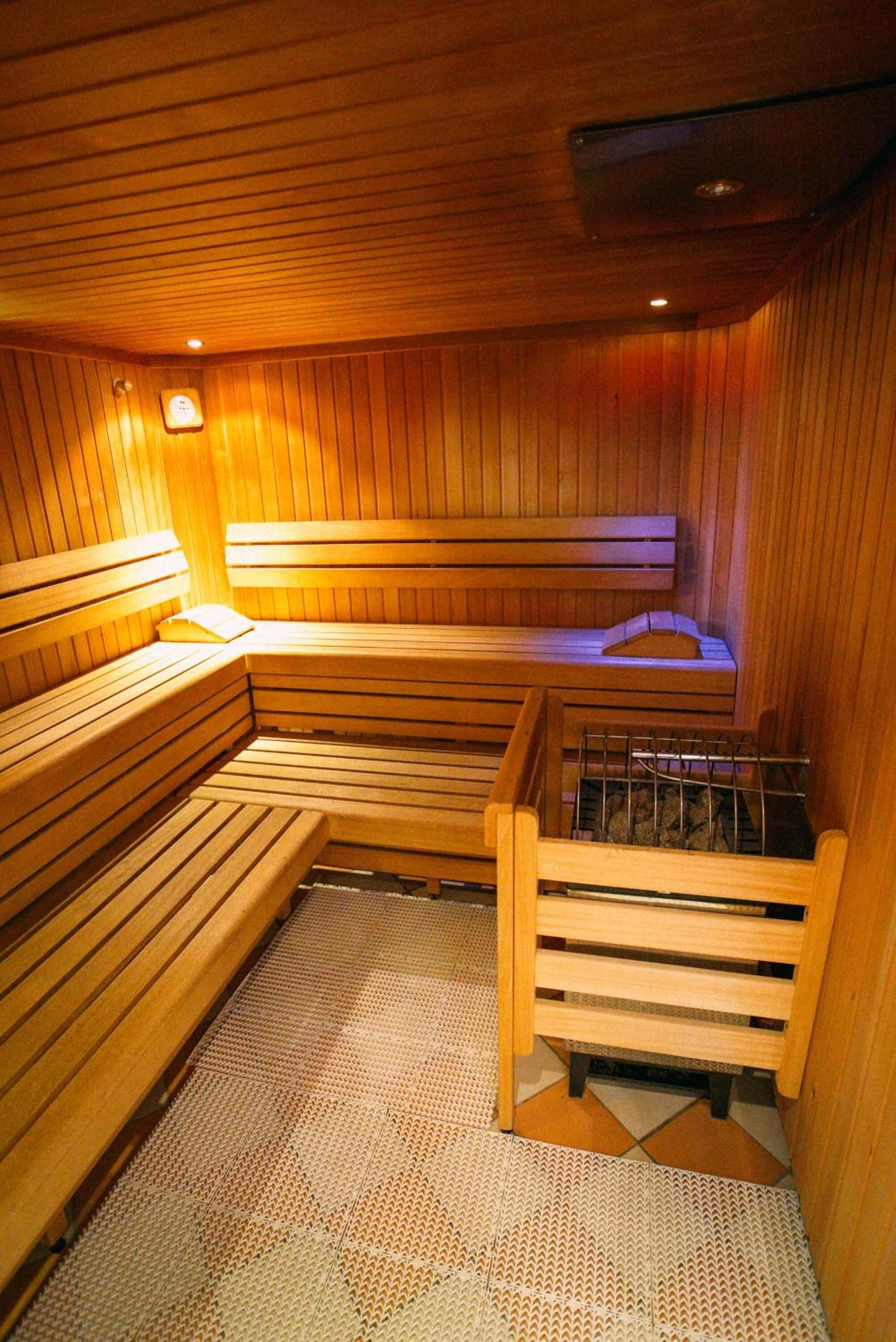 Una sauna con bancos de madera y una banca con un estante de metal.