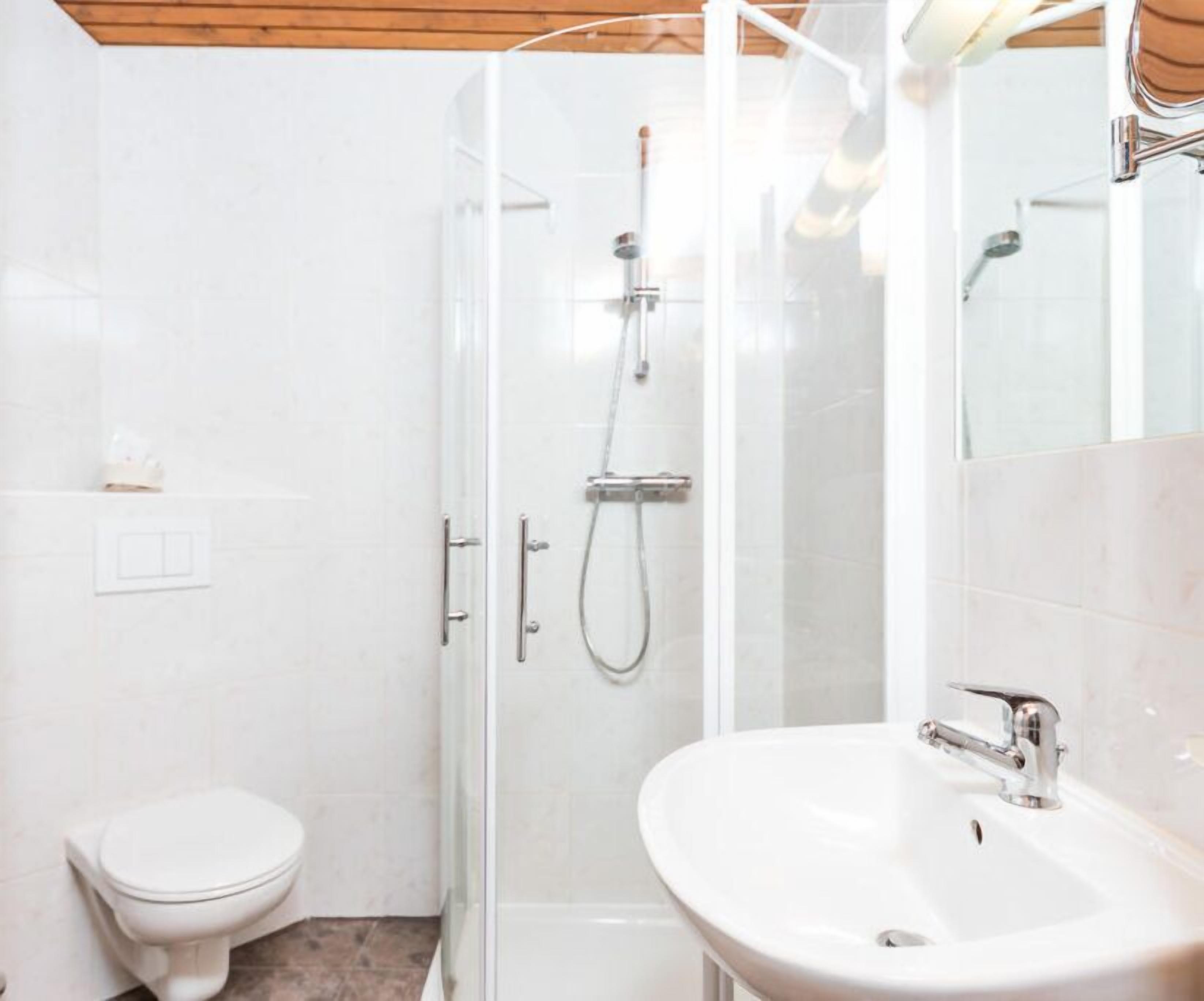 A modern bathroom with a glass-enclosed shower, a white toilet, and a sink with a mirror.