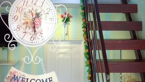 A staircase with a wooden handrail and a decorative clock with a floral design. - Sweet Lighthouse Homestay (Pak Chong)