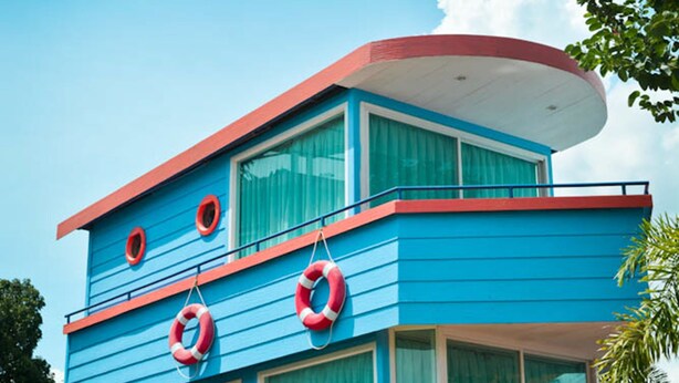 A multi-story building with a blue exterior and red trim, featuring large windows and a balcony. - Sweet Lighthouse Homestay (Pak Chong)