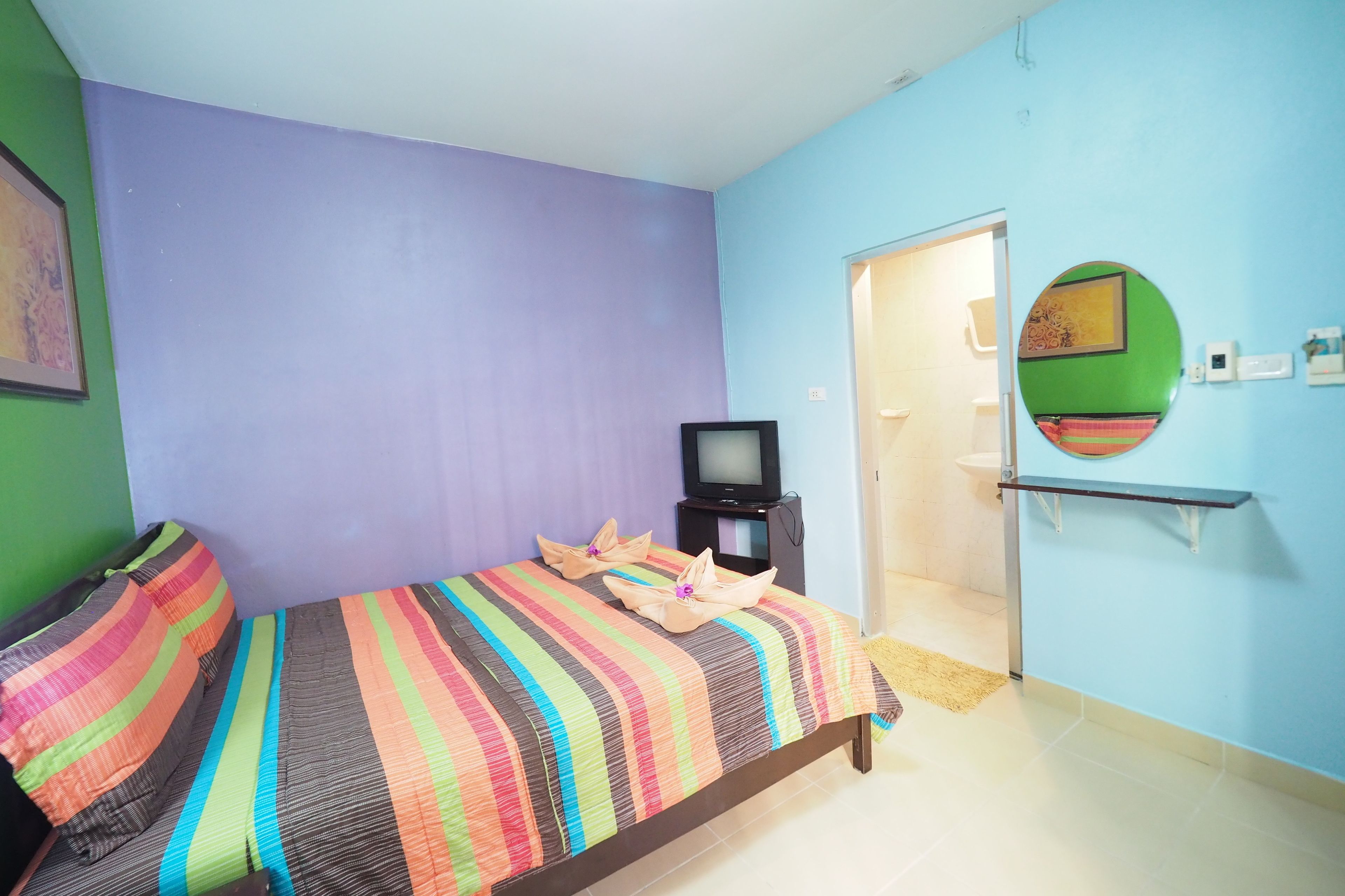 A room with a bed, a television, and a mirror on the wall.