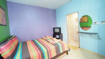 A room with a bed, a television, and a mirror on the wall.