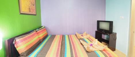 Une chambre avec un lit, une télévision et un tableau au mur.