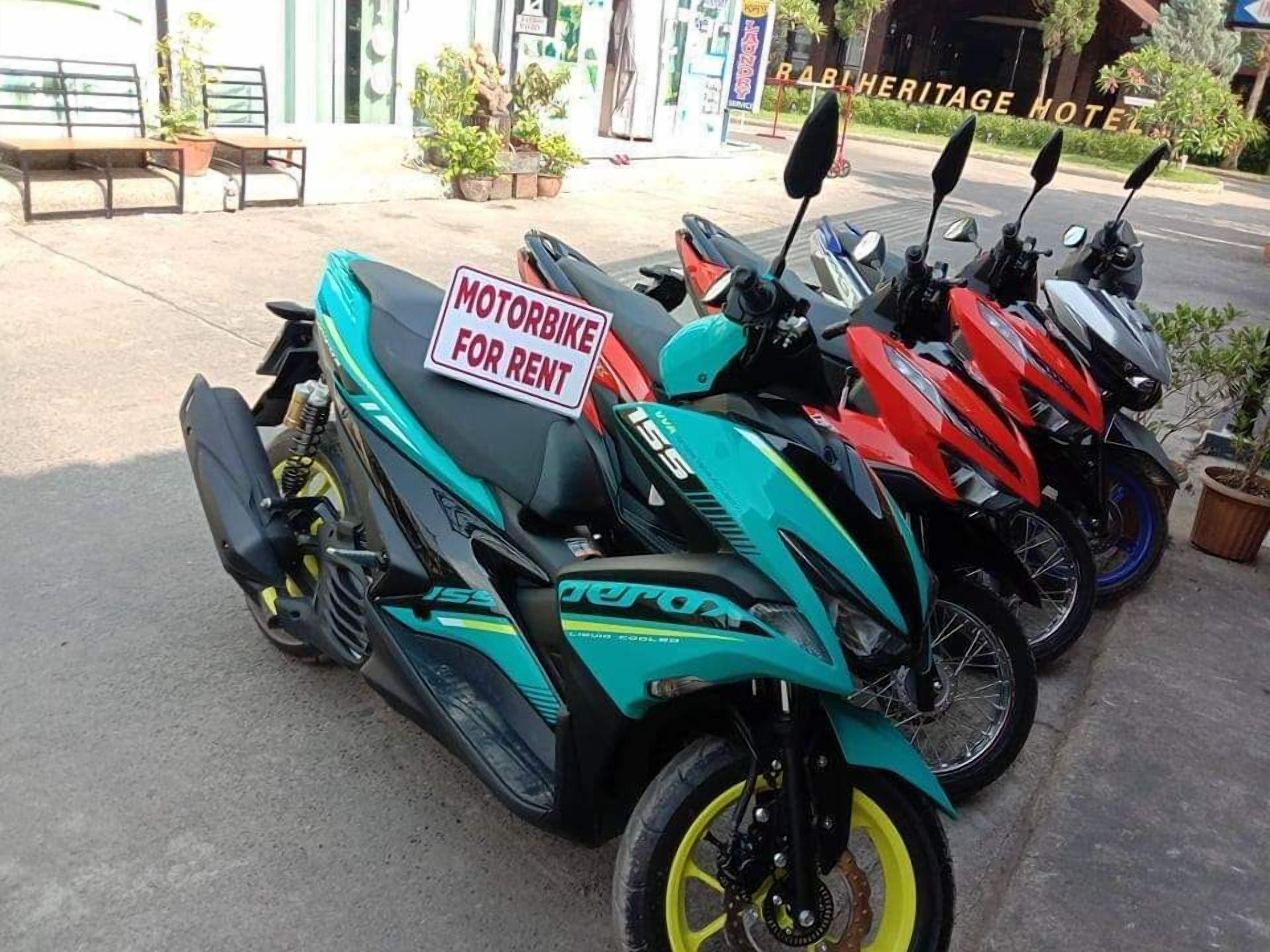 Eine Reihe geparkter Motorräder, mit einem Schild, das darauf hinweist, dass sie vermietet werden.