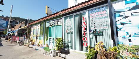A storefront with a prominent 'POPEYE TATTOO' sign, a bench, and potted plants outside.