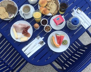 A table set with breakfast items including bread, eggs, cheese, ham, croissants, and fruits. - La Reine Jane (Hyères)