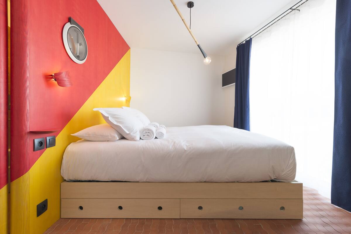 Un dormitorio moderno con cama, un reloj de pared y un diseño geométrico único en la pared.
