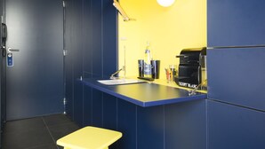 A small, brightly lit kitchen area with a yellow countertop, a coffee machine, and a sink. - La Reine Jane (Hyères)