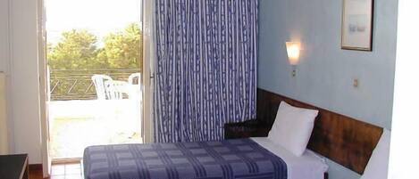 Habitación de hotel con dos camas, cabecero de madera, ventana con cortinas y una lámpara fijada a la pared.