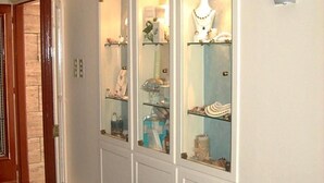 A hallway with a gift shop featuring glass display cases. - Oasis Hotel (Kalymnos)