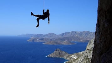 Una persona haciendo bungee jumping desde un acantilado, con vista al océano y montañas al fondo.
