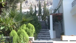 A staircase leading up to a white building with a garden area on the left. - Oasis Hotel (Kalymnos)