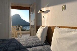 Habitación de hotel con cama, vista a la montaña y balcón con mesa y sillas.