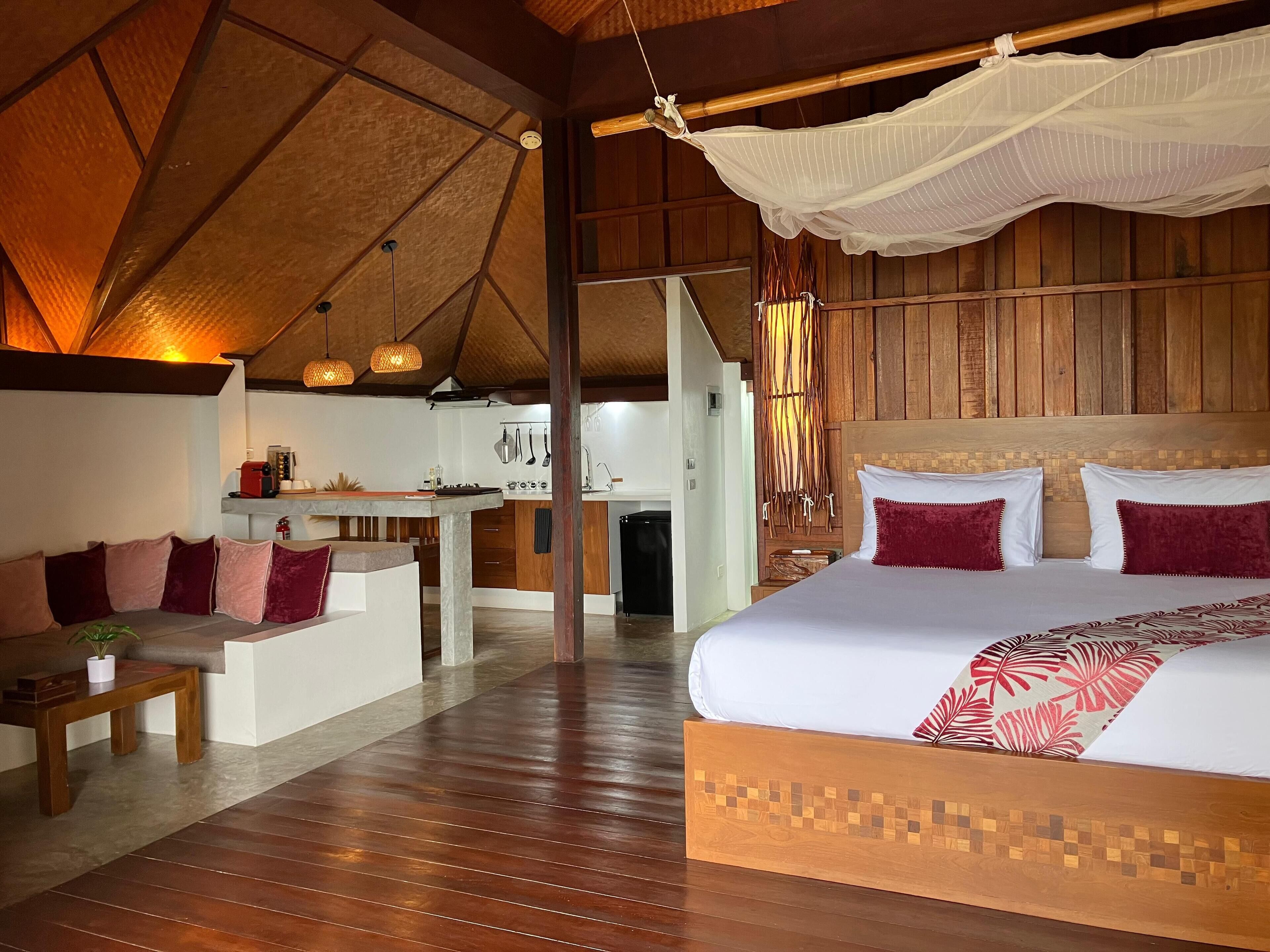 Ein geräumiges Zimmer mit einem großen Bett, Holzboden und einem Essbereich.
