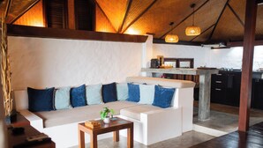 A modern living area with a sofa, coffee table, and kitchen in the background. - The Place Luxury Boutique Villas (Koh Tao)