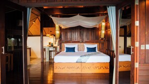 A wooden room with a large bed, a small table, and a chair. - The Place Luxury Boutique Villas (Koh Tao)