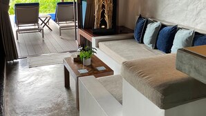 A cozy living area with a sofa, chairs, and a coffee table. There is a view of greenery outside. - The Place Luxury Boutique Villas (Koh Tao)