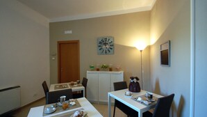 Un comedor con una mesa dispuesta para dos, un reloj en la pared y un aparador con adornos.