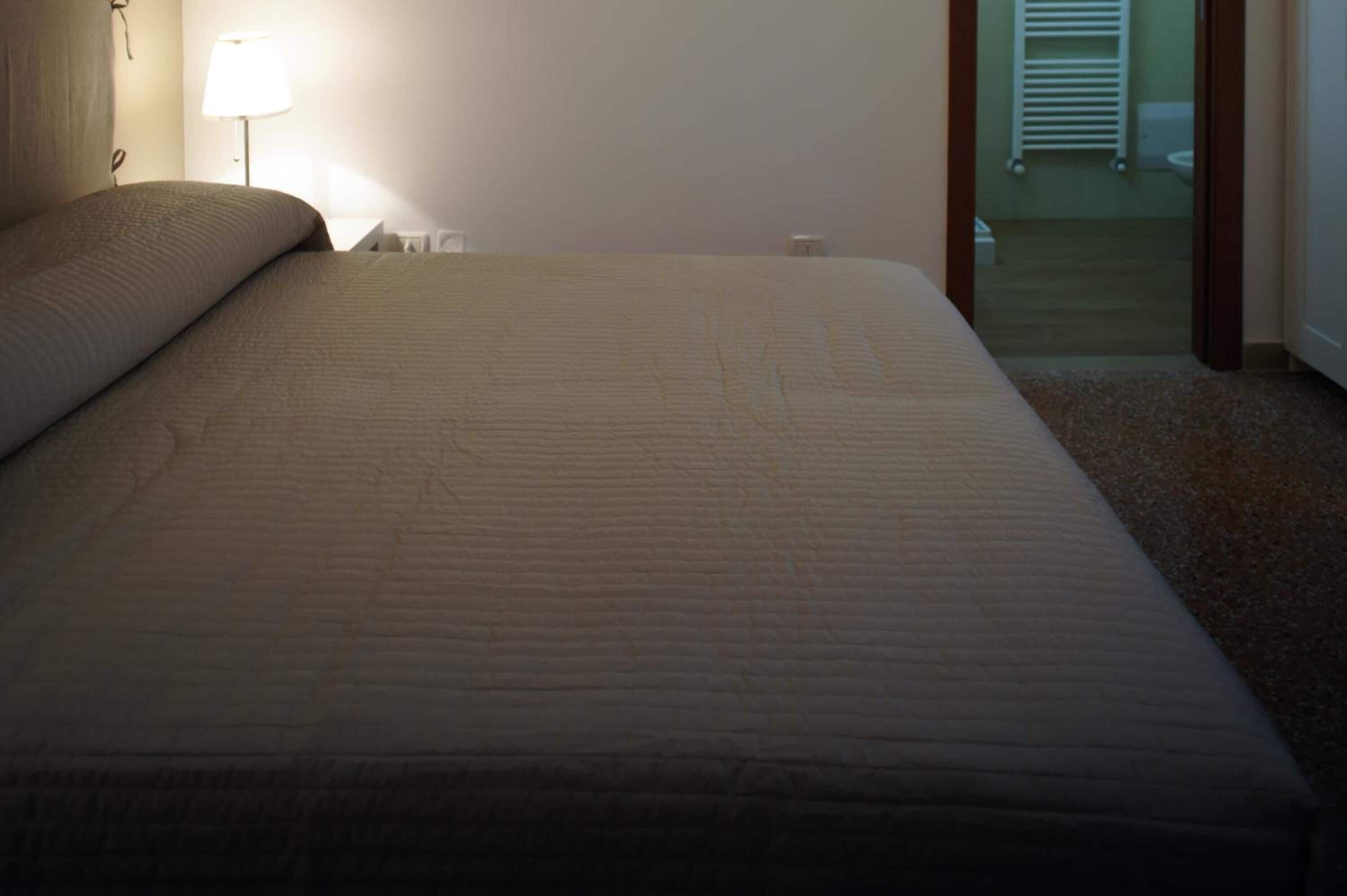 A hotel room with a large bed, a bedside lamp, and a view of the bathroom.