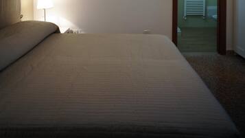 A hotel room with a large bed, a bedside lamp, and a view of the bathroom.