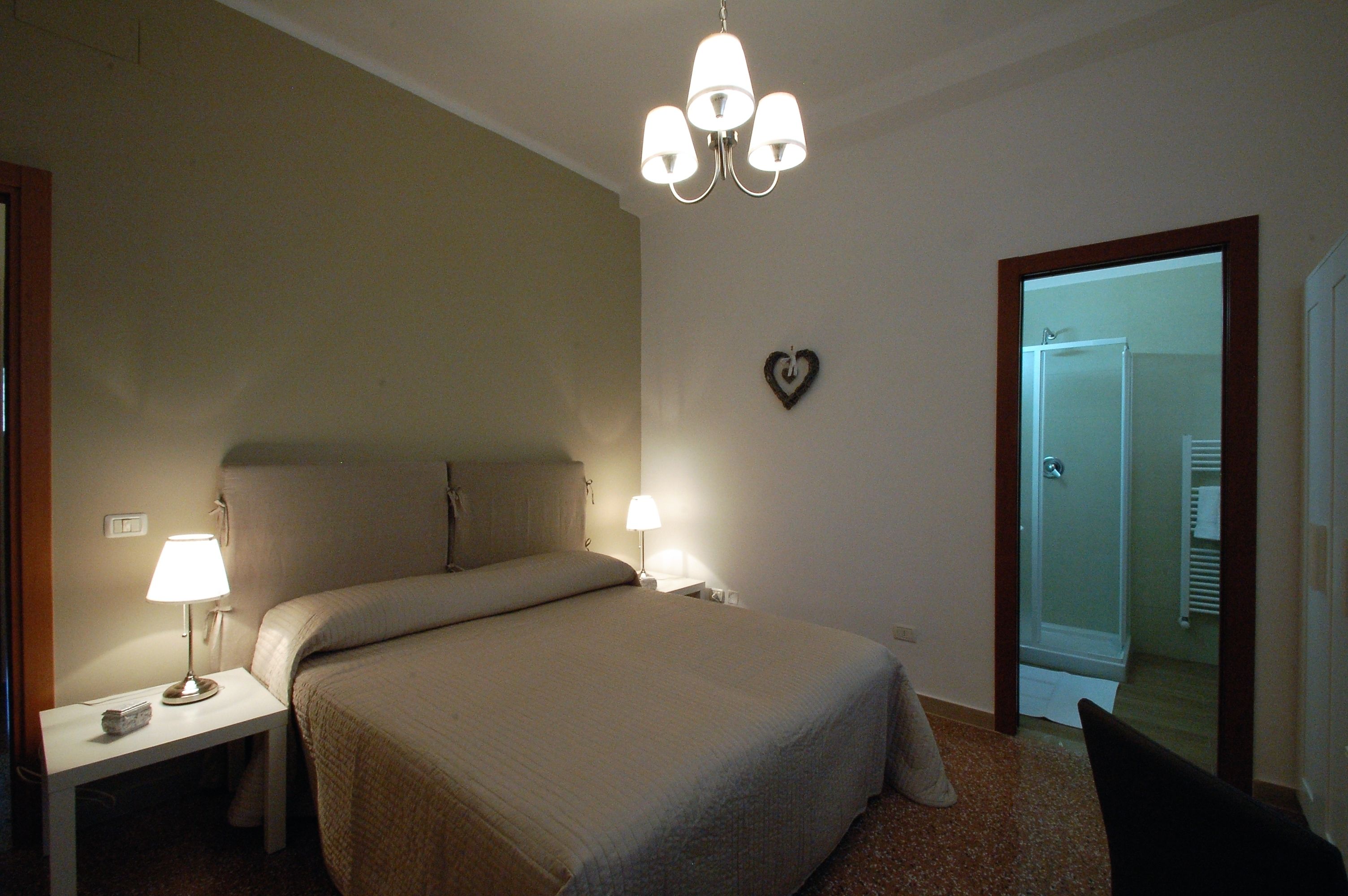 Una camera da letto con un letto grande, due lampade ai comodini, un lampadario e una decorazione a forma di cuore sulla parete.