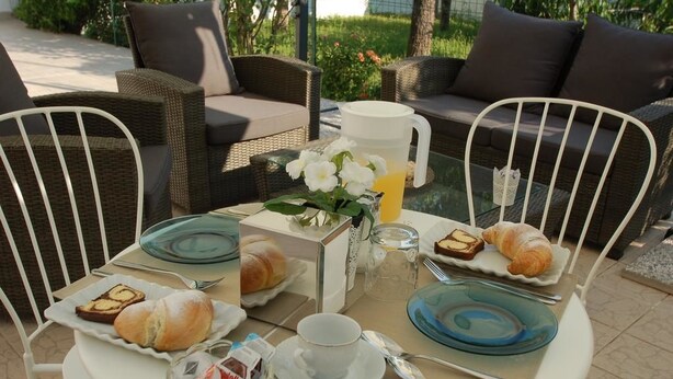 Un desayuno con cruasanes, una cafetera y una mesa de vidrio al aire libre.