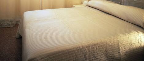 A neatly made bed with a quilted cover and a wooden headboard.