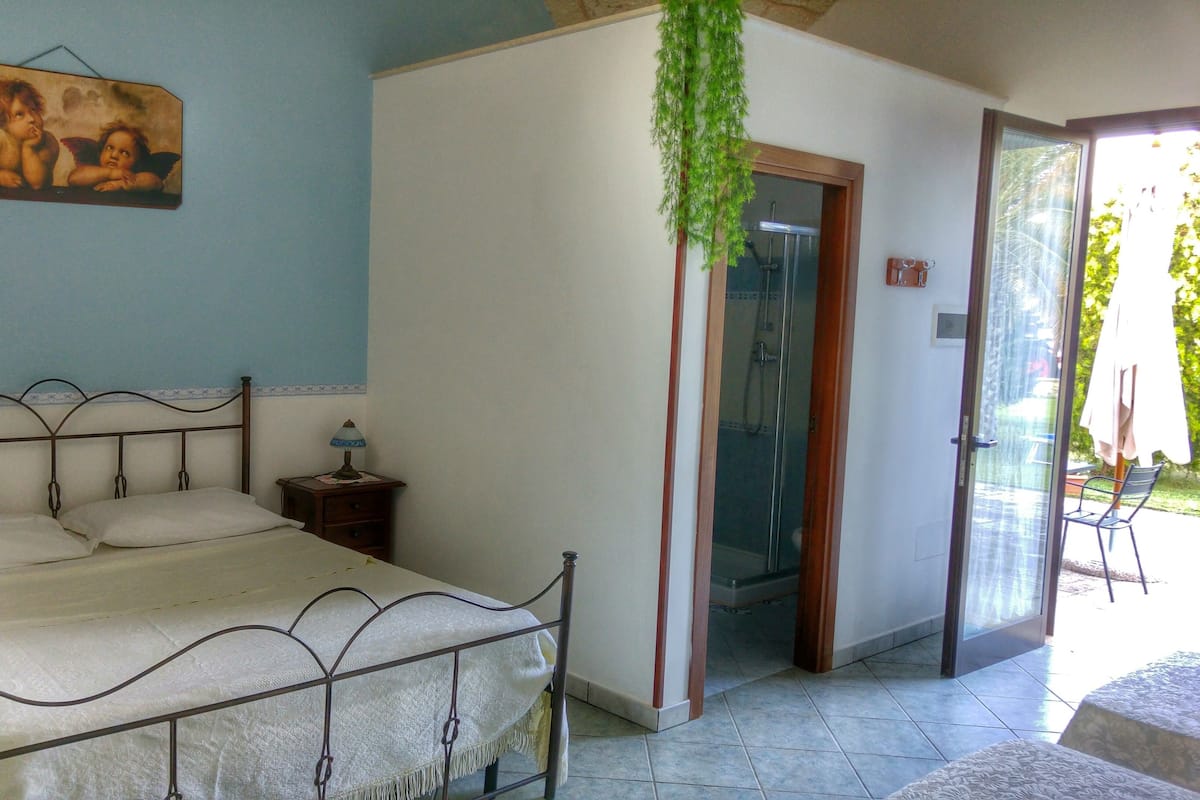 Un dormitorio con estructura de cama metálica, una mesita de noche con lámpara y un cuadro en la pared.