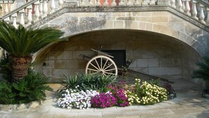 A stone staircase with balustrades leading to a door with a large wheel. - Villa Papaleo (Bagnolo del Salento)