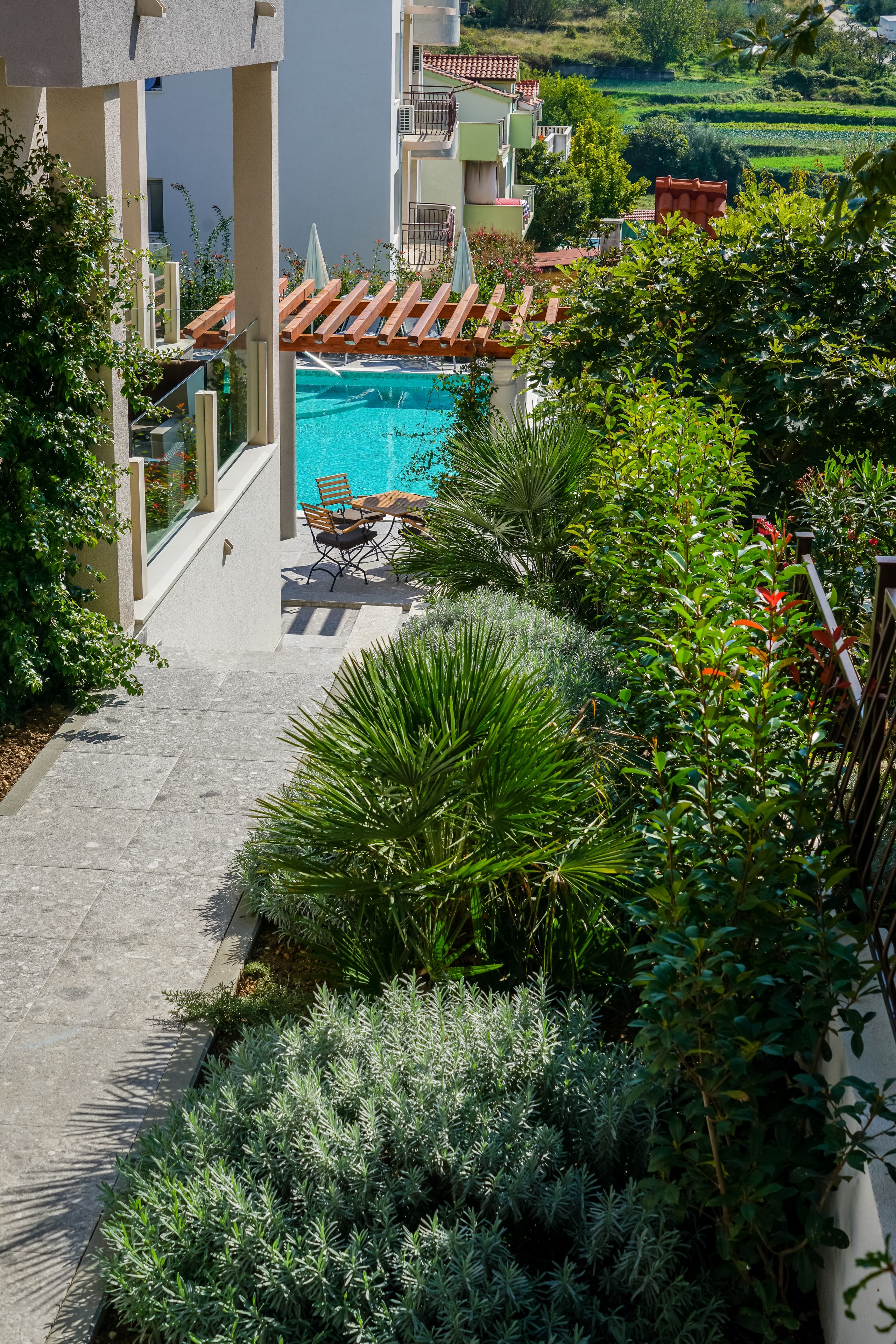 Un espace piscine offrant une vue sur un jardin luxuriant et un bâtiment doté de balcons.
