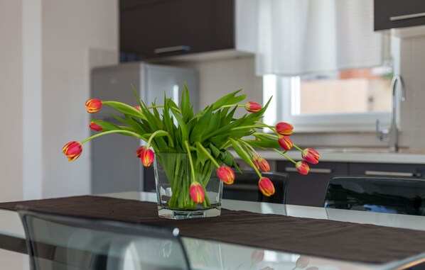 A glass vase with tulips on a table in a modern kitchen.