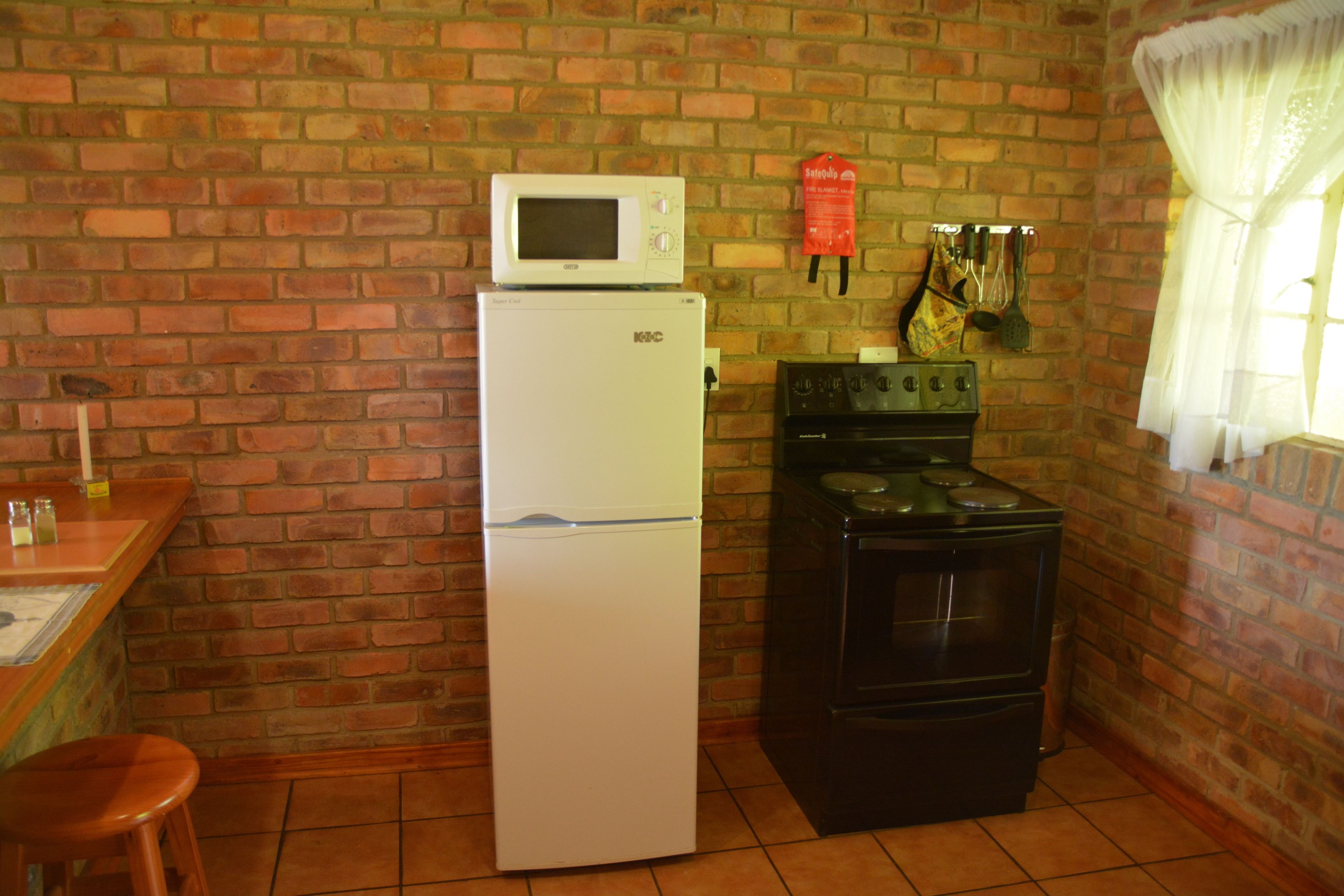 Una cocina con refrigerador, estufa y pared de ladrillo.