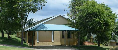 A single-story building with a covered patio area, surrounded by well-maintained lawns and trees.
